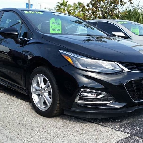Black Chevrolet Cruze with factory silver alloy wheels on a dealership lot